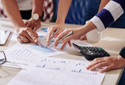 Group of business people pointing at financial document with chart when discussing expenses and revenue